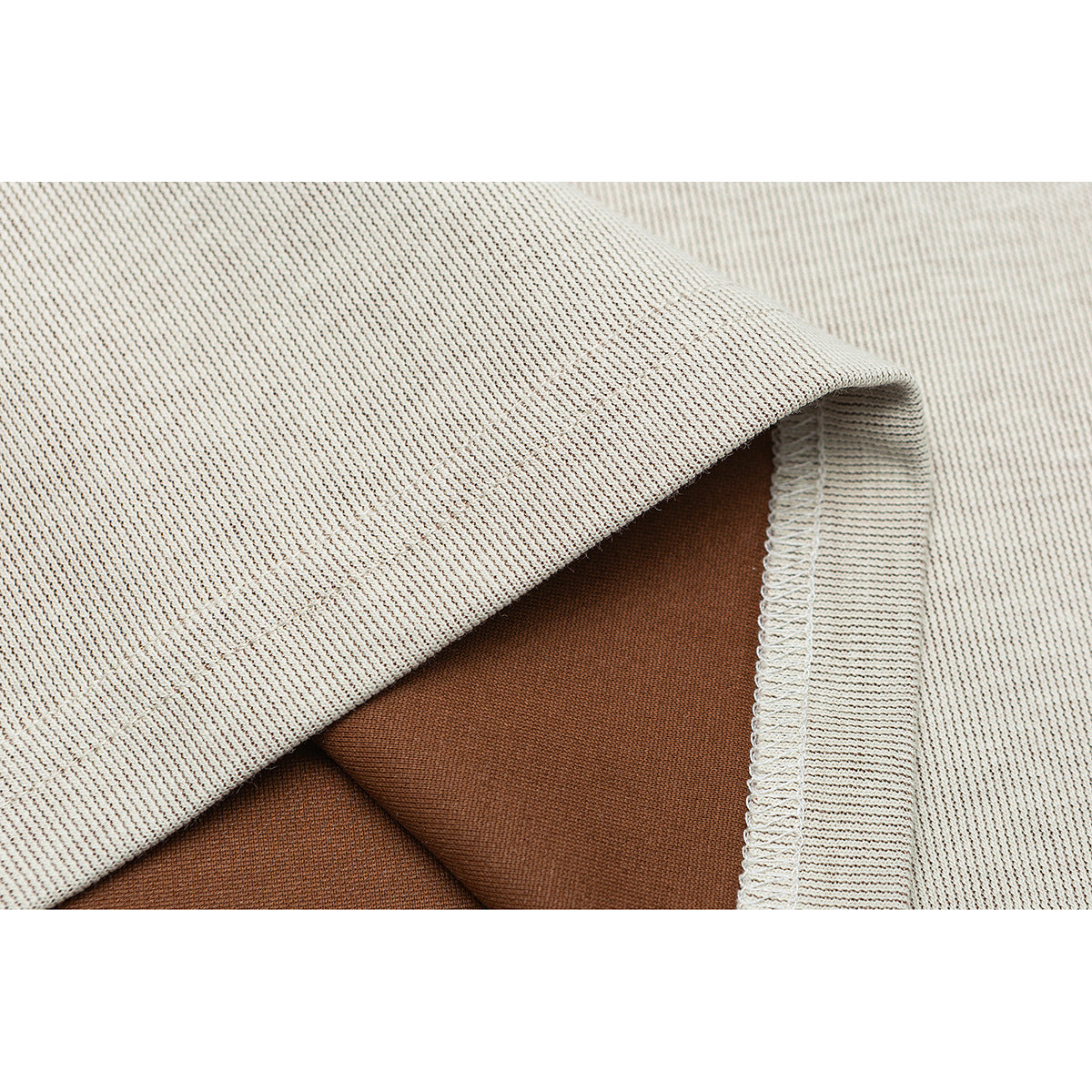 Close-up of a cream knit shirt's folded hem and stitched seam.