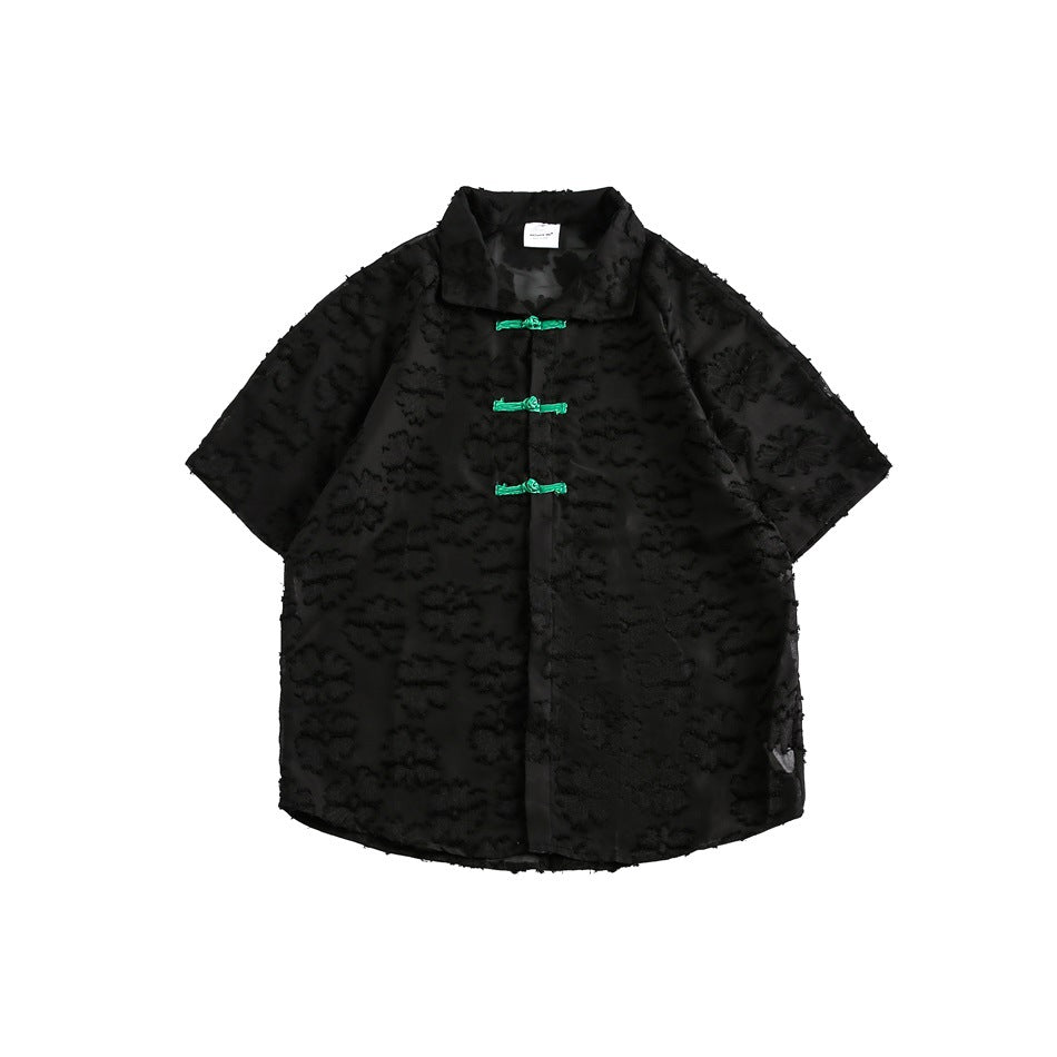 Black short-sleeve shirt with raised floral texture and three green knotted closures, flat lay front view