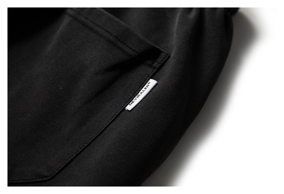 Close-up of a black pants pocket seam with a small white woven label.