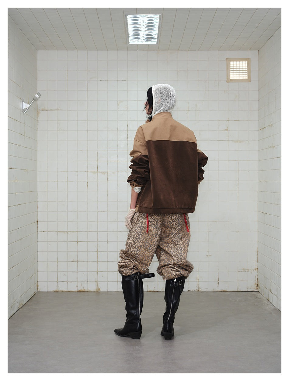 Rear view of a model wearing a two-tone brown jacket, leopard-print trousers and black boots.