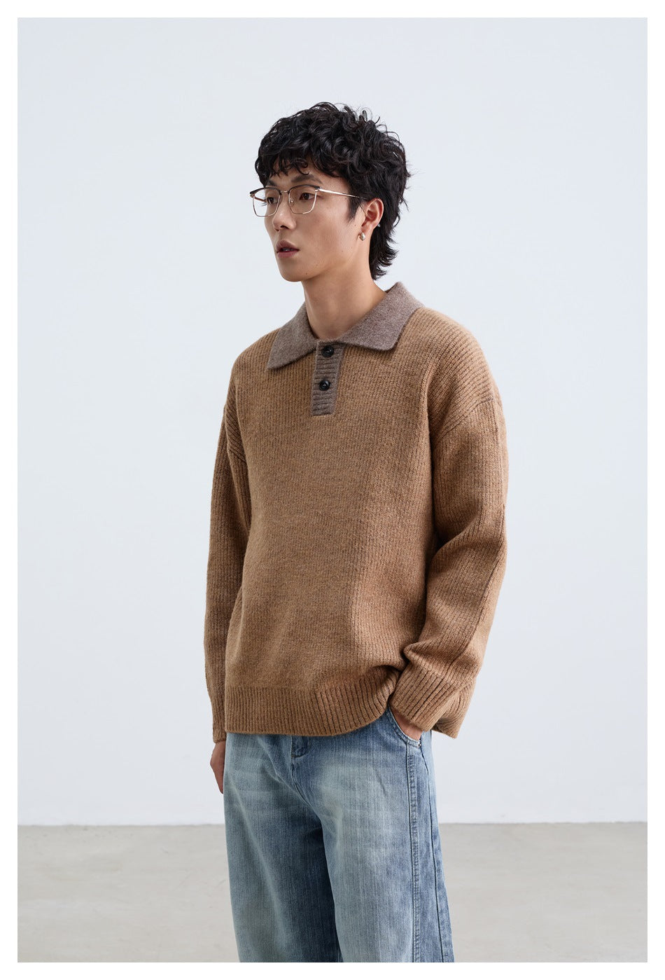 Model wearing a camel-brown knit polo sweater with a contrasting taupe collar and blue jeans, shown from the waist up.