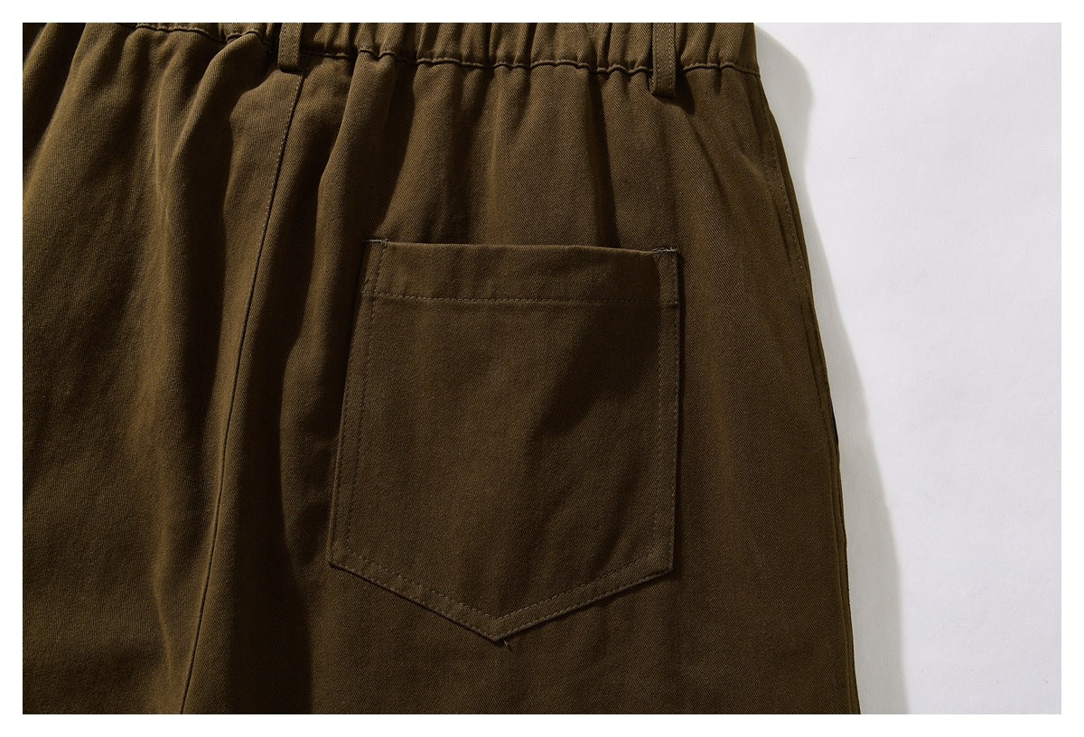 Close-up of the back patch pocket and gathered waistband on olive-brown trousers.