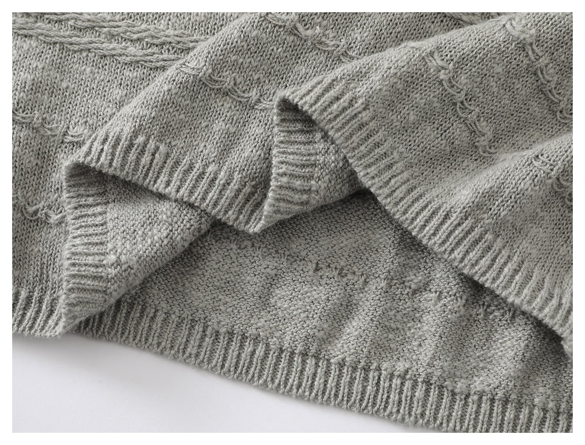 Close-up of a light gray knitted garment's ribbed hem and folded edges, showing textured stitches.