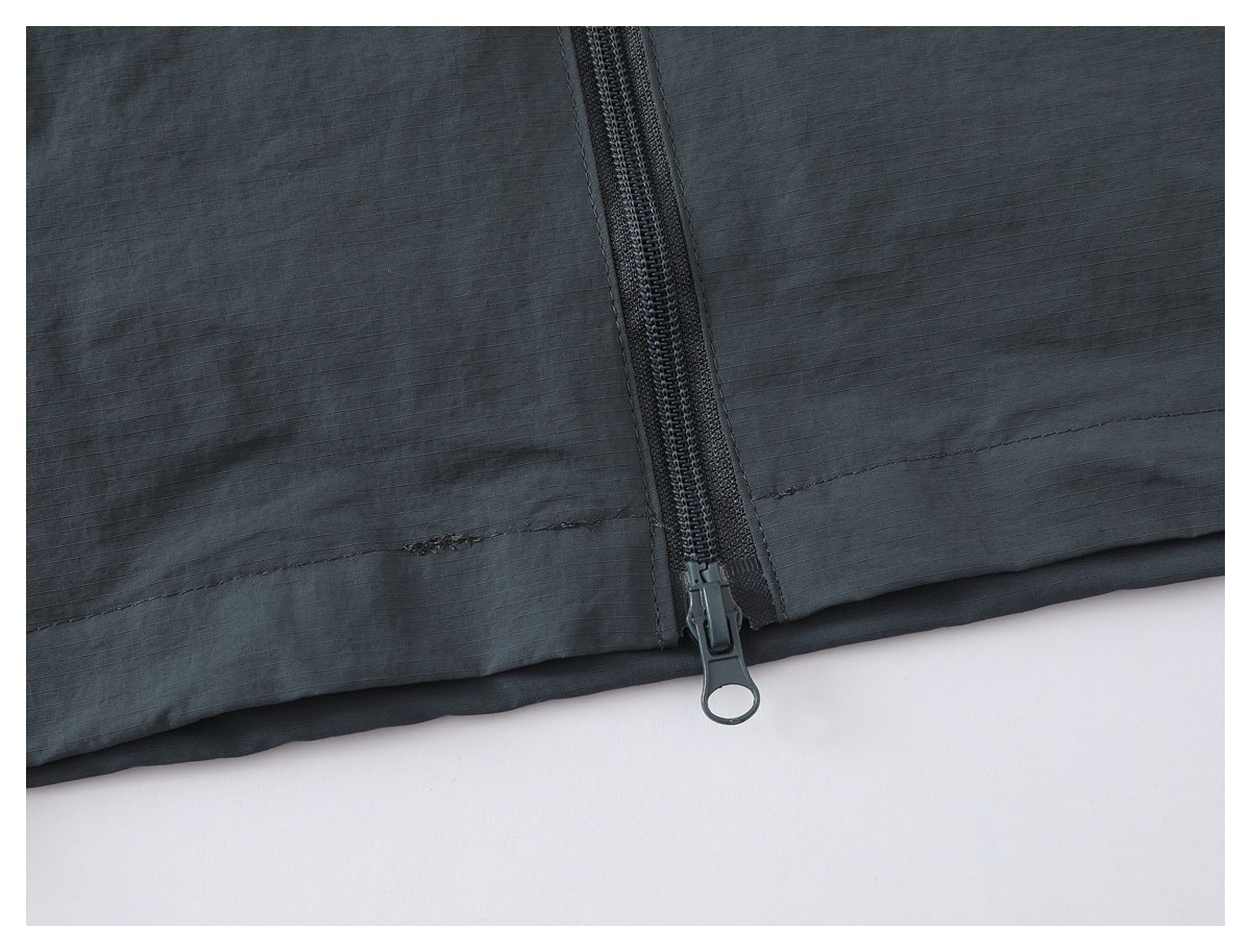 Close-up of the charcoal gray jacket hem and center zipper with a large ring pull.
