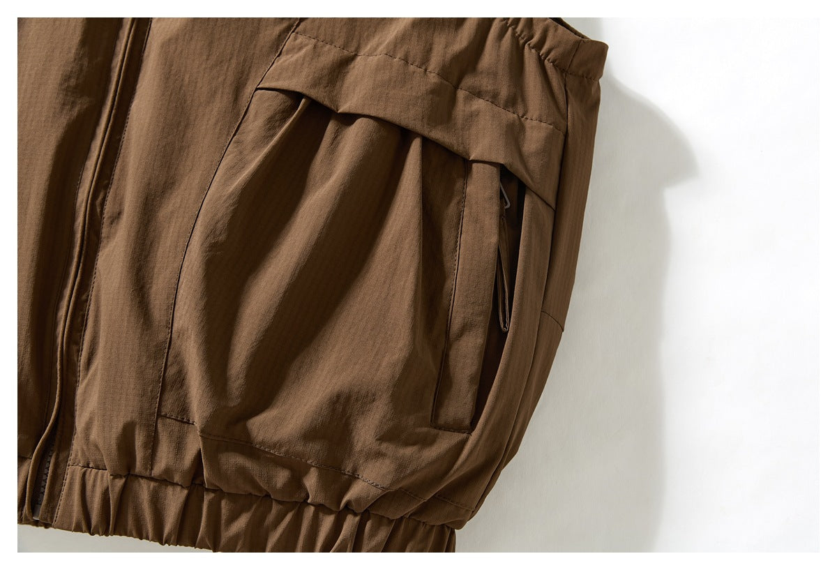 Close-up of a large brown jacket pocket with a flap, zipper, and gathered hem below.