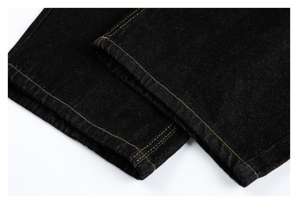 Close-up of the finished hems and seams of black jeans with gold stitching.