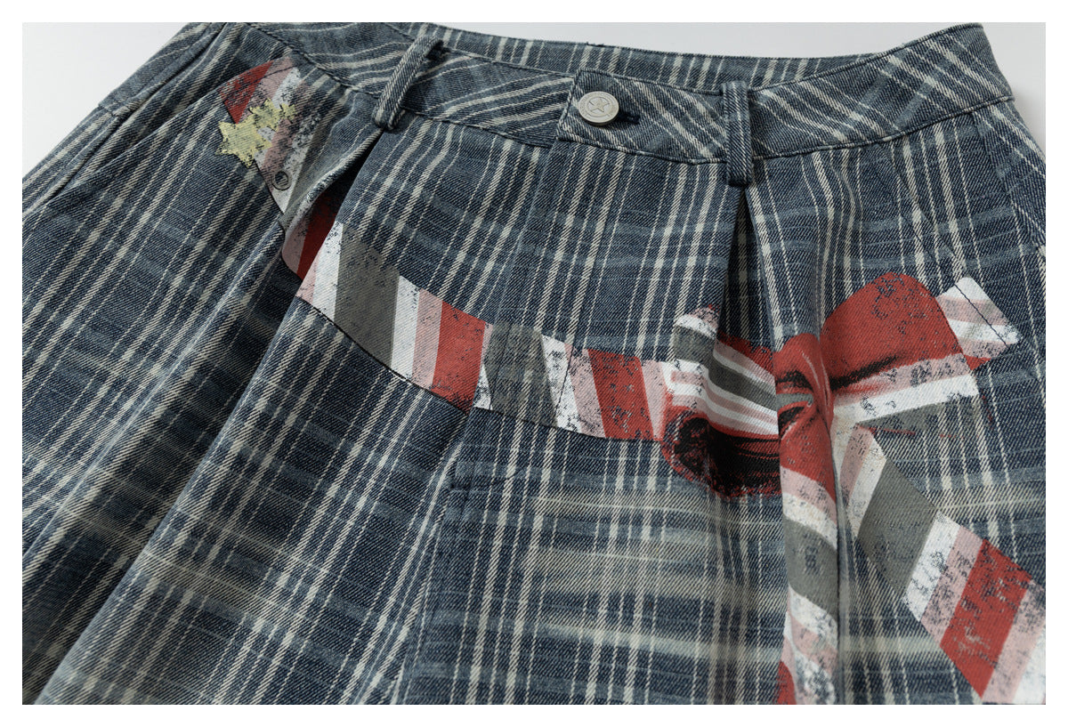 Close-up of blue-gray plaid shorts with a distressed red, white, and gray graphic across the front.