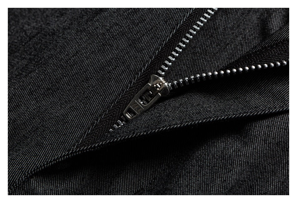 Close-up of a metal zipper on dark charcoal trousers.