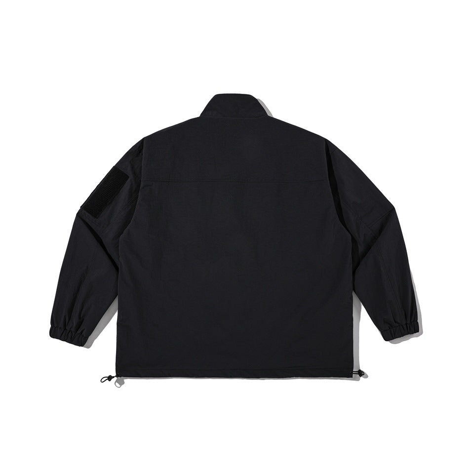 Back view of a black jacket with a high collar, elastic cuffs, sleeve patch and adjustable hem cords.