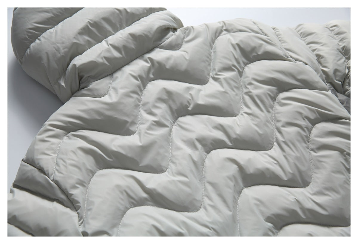 Partial view of a light gray padded jacket laid flat, showing its wavy quilted stitching.
