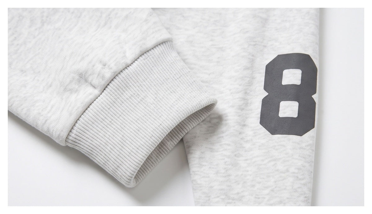 Close-up of a light gray marled sleeve cuff beside a dark number 8 printed on the garment.