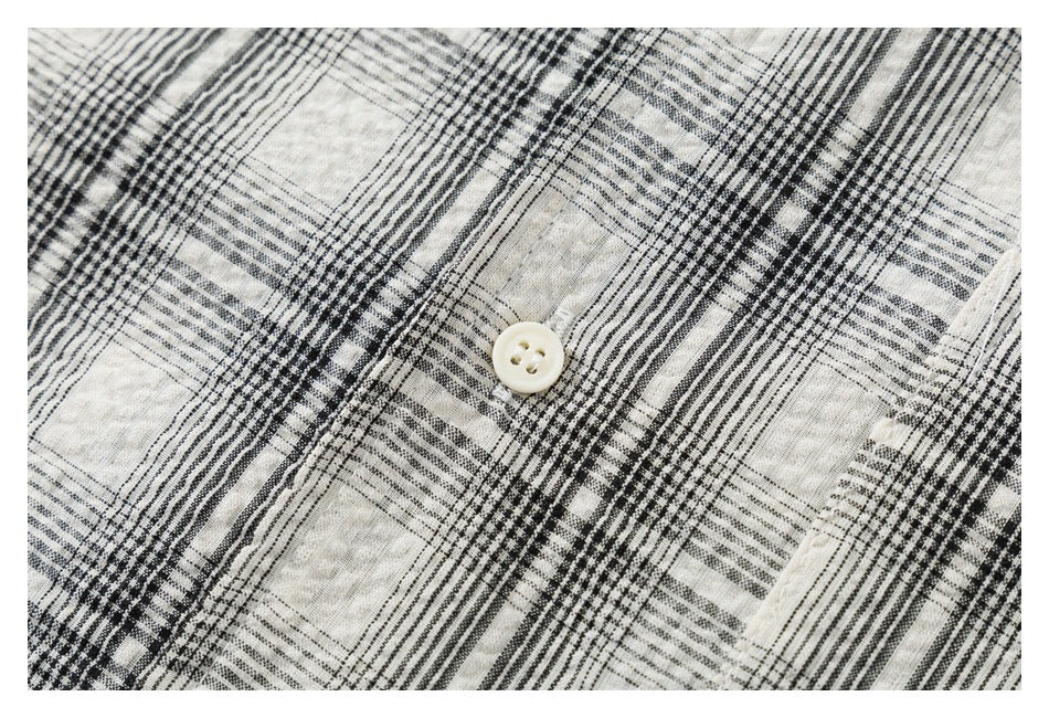 Close-up of a cream and black plaid shirt with a small cream four-hole button.