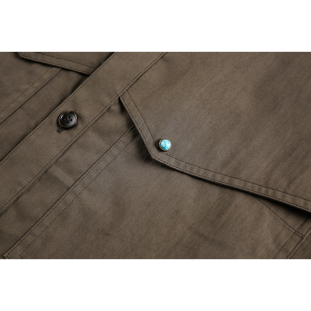 Close-up of a brown shirt pocket flap with a turquoise button beside the black front buttons.