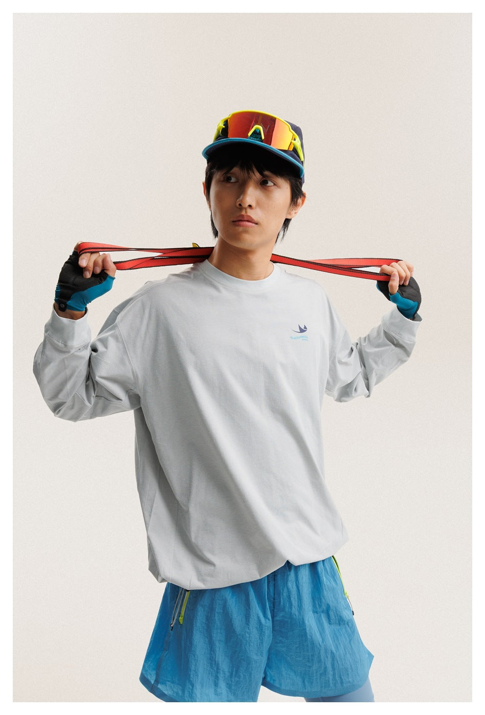 Closer view of a model in a light gray long-sleeve shirt and bright blue shorts.
