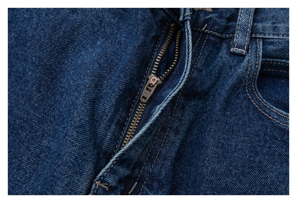 Close-up of the partially open zipper fly and front pocket on dark blue jeans.