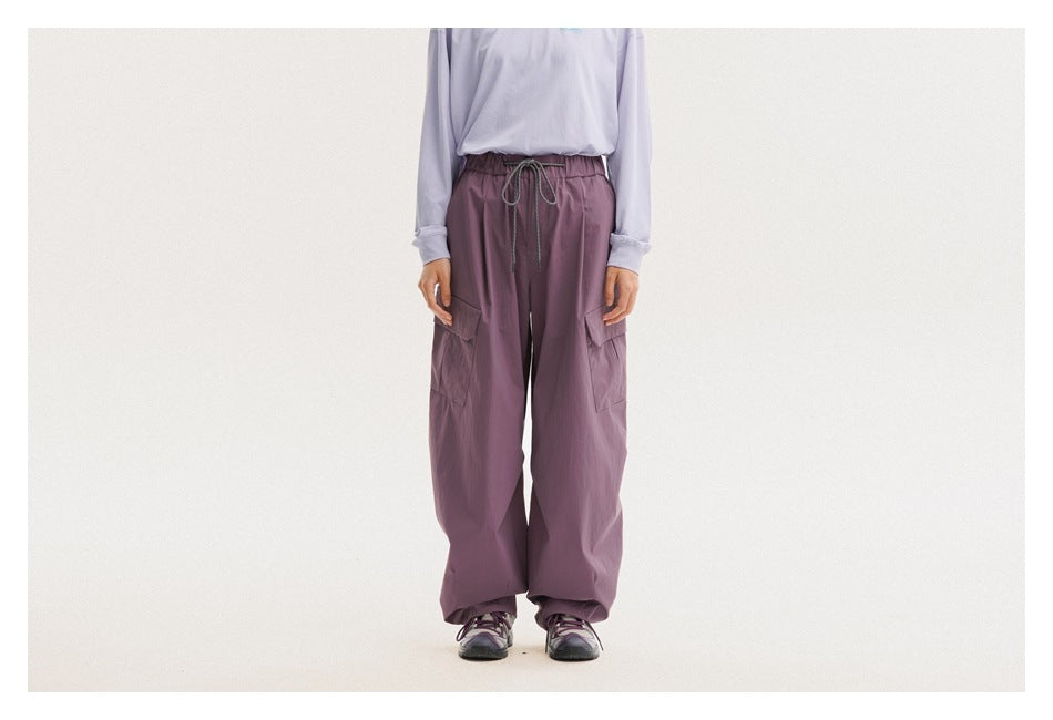 Front view of a model wearing mauve wide-leg cargo pants with a drawstring waist and flap pockets.