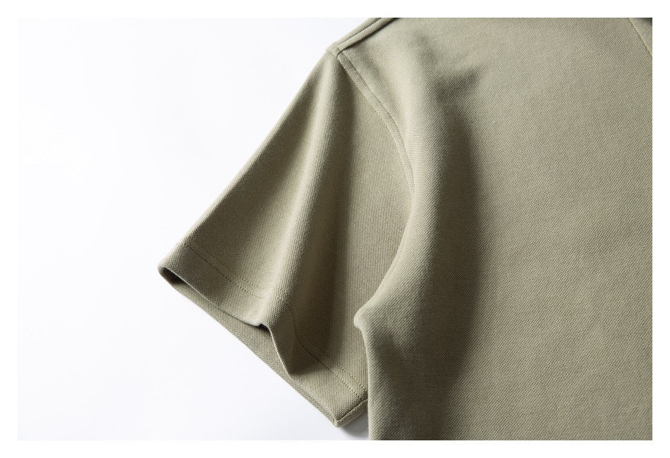 Close-up of the short sleeve and shoulder seam on a muted olive-beige garment.