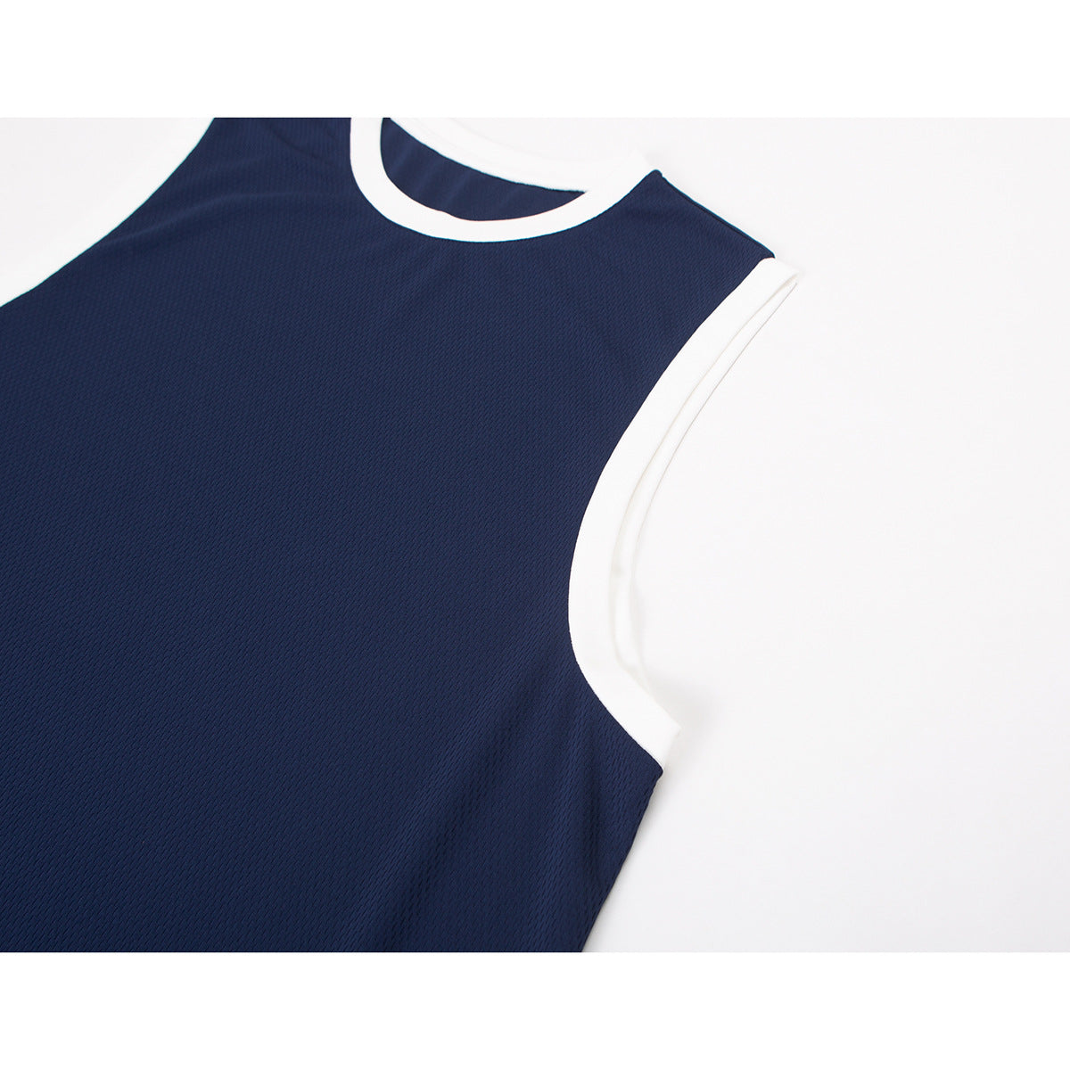 Close-up of a navy sleeveless jersey top with white trim around the crew neck and armhole.