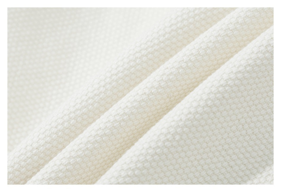 Extreme close-up showing the woven texture of ivory fabric.
