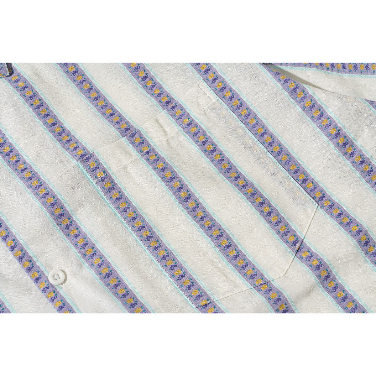 Close-up of the ivory shirt's purple floral stripes, turquoise edging, pocket seam, and white button.