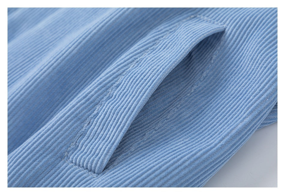 Close-up of a slit pocket on light blue ribbed corduroy fabric.