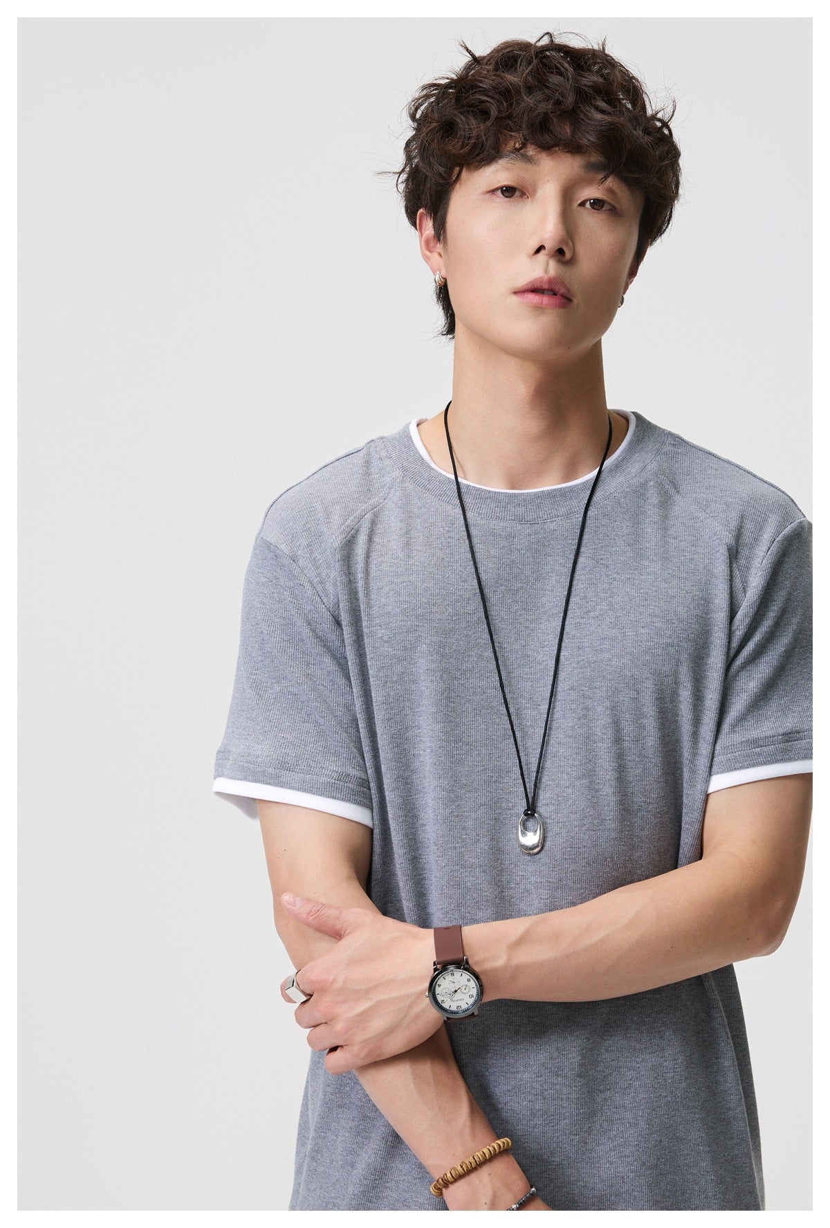 Close front view of a model in a heather gray T-shirt with white neckline and sleeve trim.