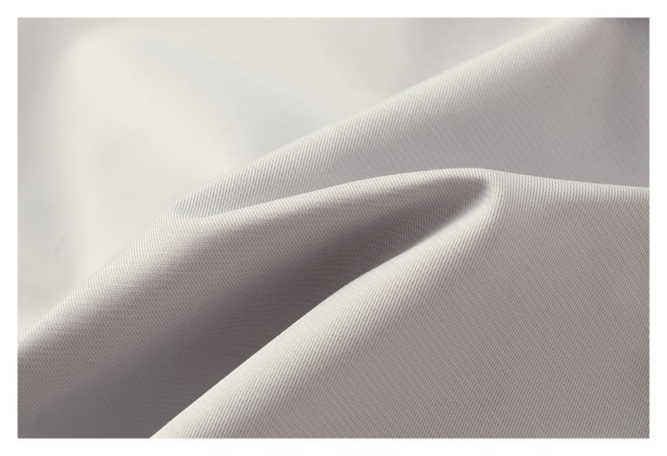 Close-up of light gray fabric draped into soft folds, showing its fine diagonal weave.