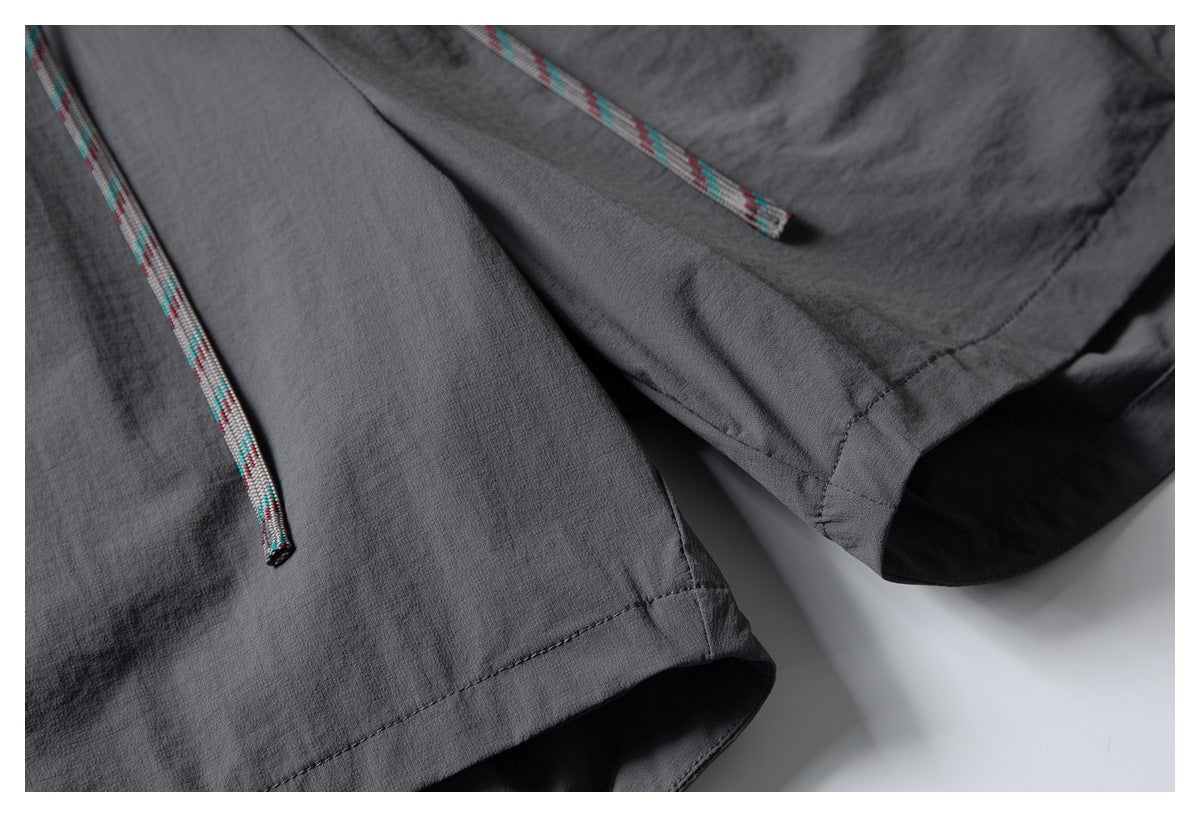 Close-up of charcoal shorts hem and seams with narrow multicolored drawcords.
