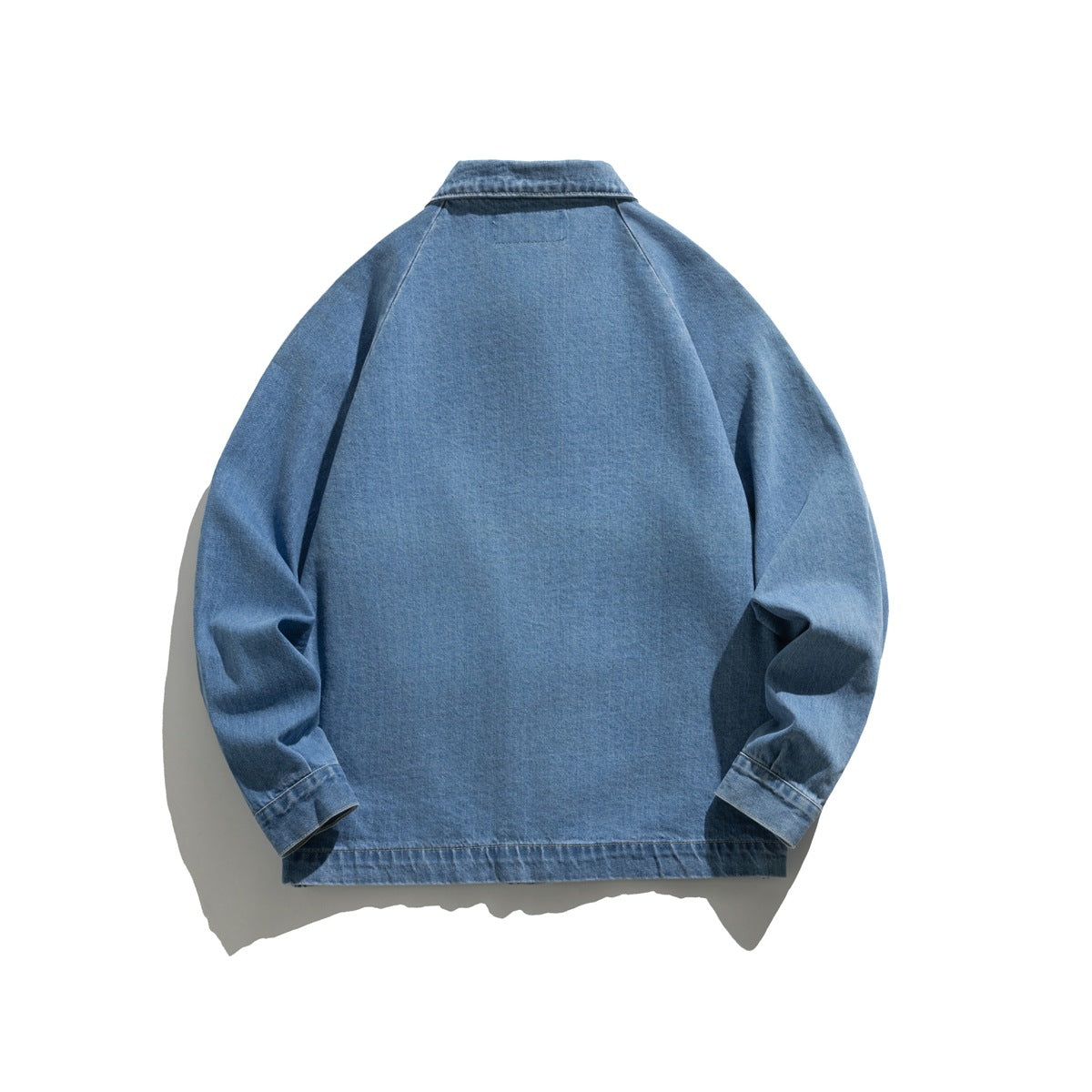 Back view of a blue denim jacket laid flat, with long sleeves, a collar, and a plain back panel.
