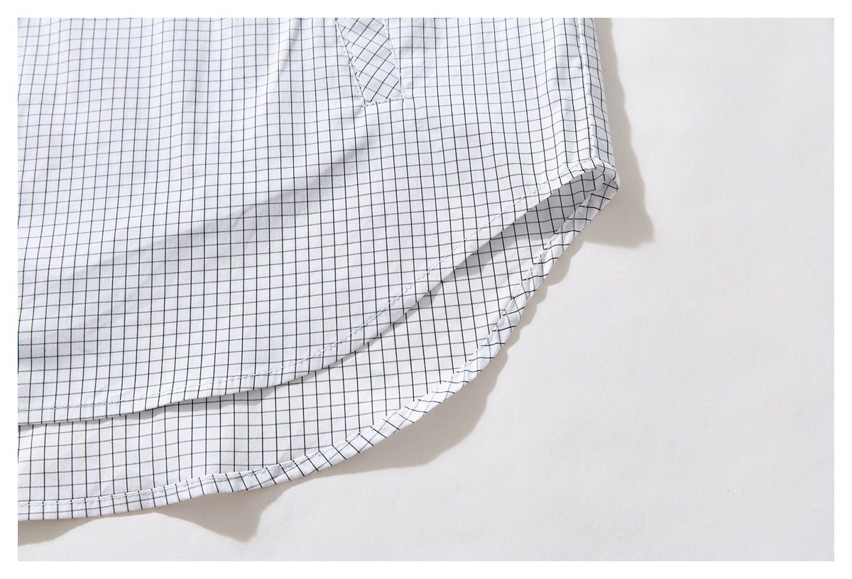 Close-up of the white shirt's curved hem and side seam in a black windowpane grid pattern.