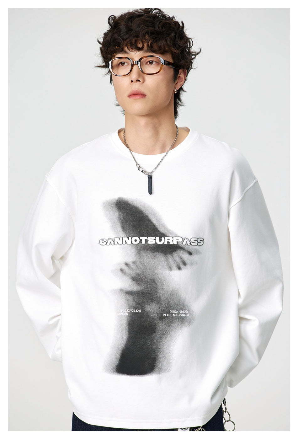 Close-up of a model wearing the white long-sleeve top showing the front blurred hands graphic and dropped shoulders