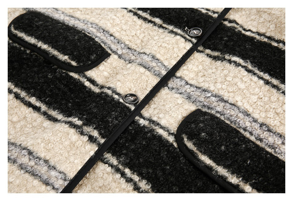 Close-up of a cream, gray, and black striped fuzzy jacket with black trim, buttons, and patch pockets.