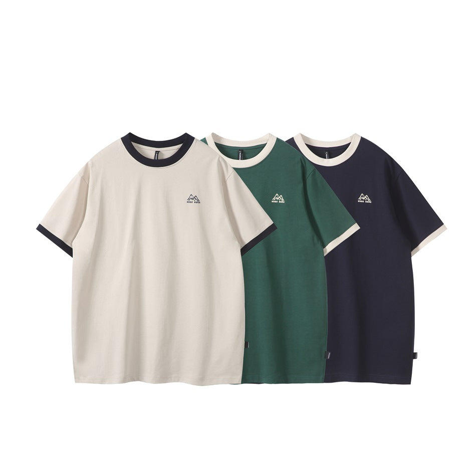Three short-sleeve T-shirts shown from the front in cream, forest green, and navy, with contrasting trim and small chest