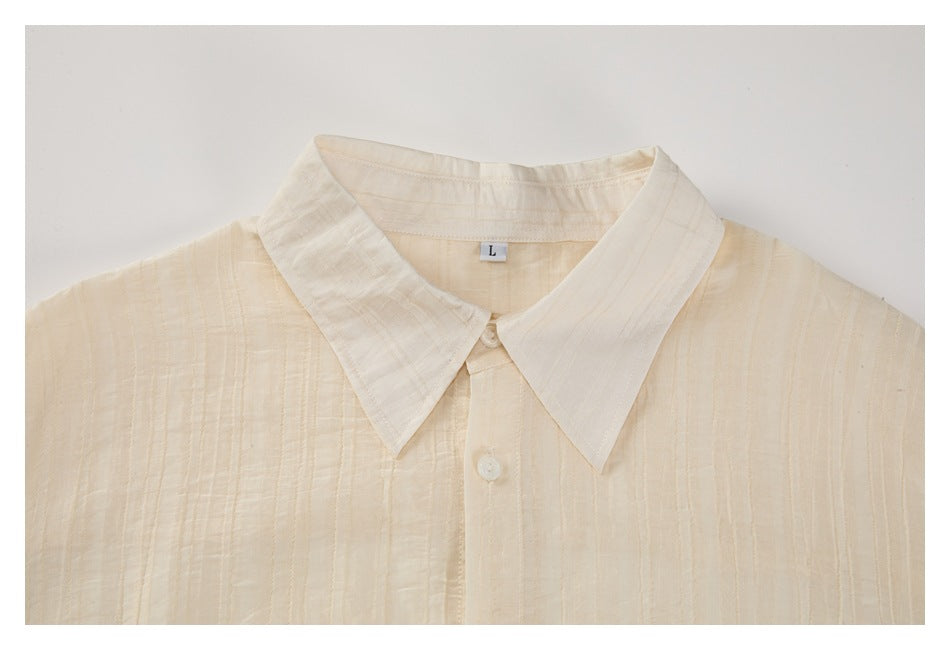 Cropped front view of an ivory button-up shirt laid flat, showing its pointed collar and subtle vertical texture.