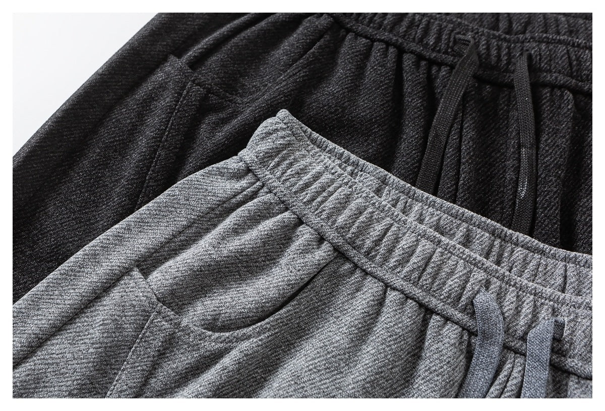 Close-up of charcoal and gray wide-leg pants showing elastic waistbands, drawstrings and side pockets.