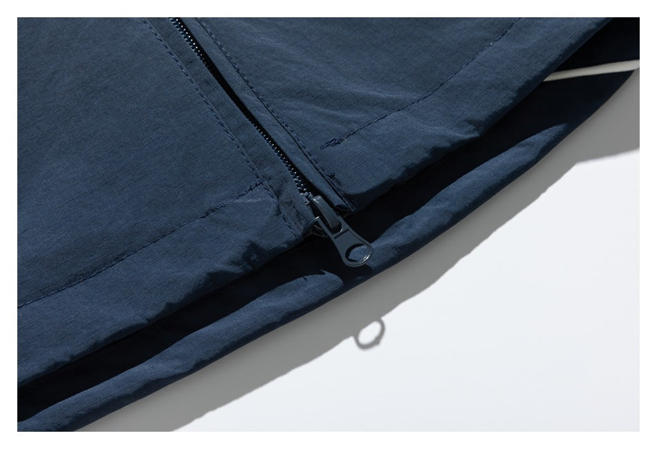Close-up of the navy jacket's front zipper and lower edge.