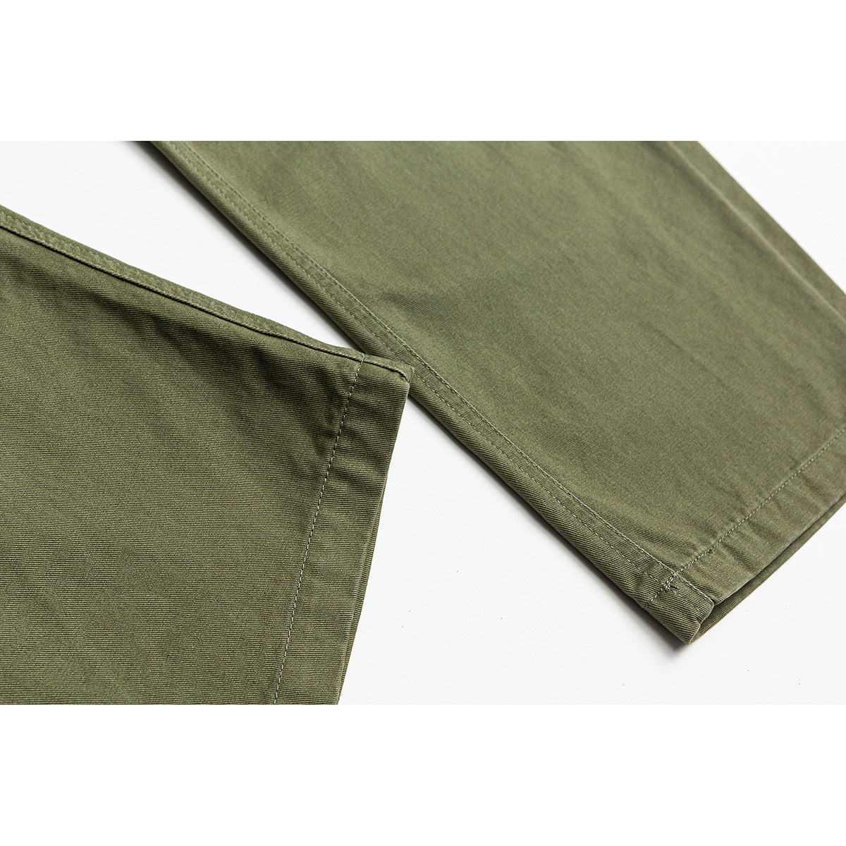 Close-up of olive-green pants showing the leg fabric, side seam, and stitched hem.