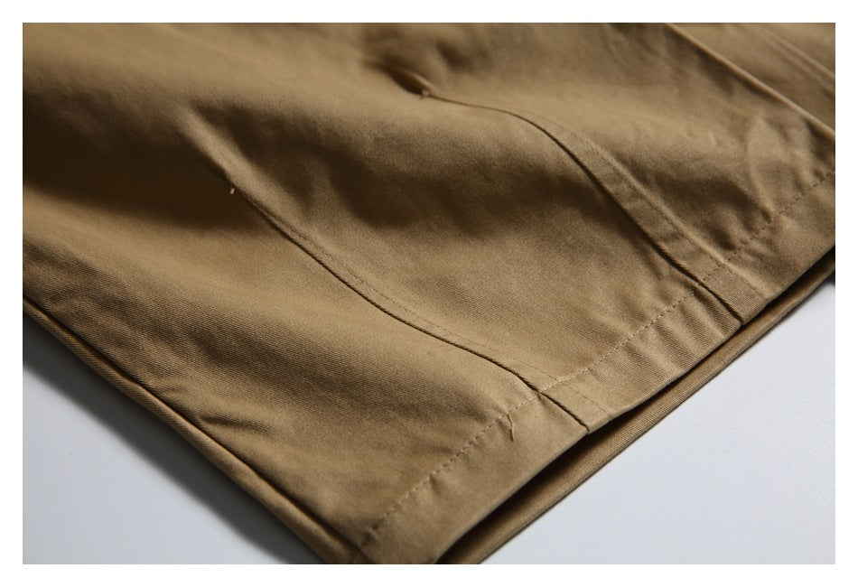 Close-up of a tan trouser leg hem with visible stitching and fabric folds.