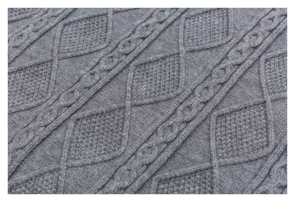 Close-up of gray cable-knit fabric with raised diamond and braided patterns.