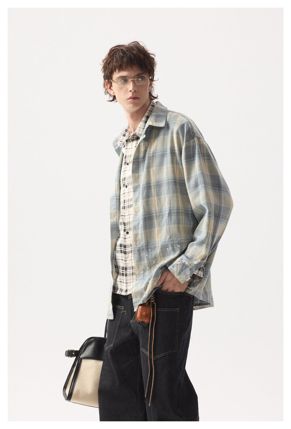 Model wears a loose blue-gray and pale yellow plaid overshirt with white splatter details.
