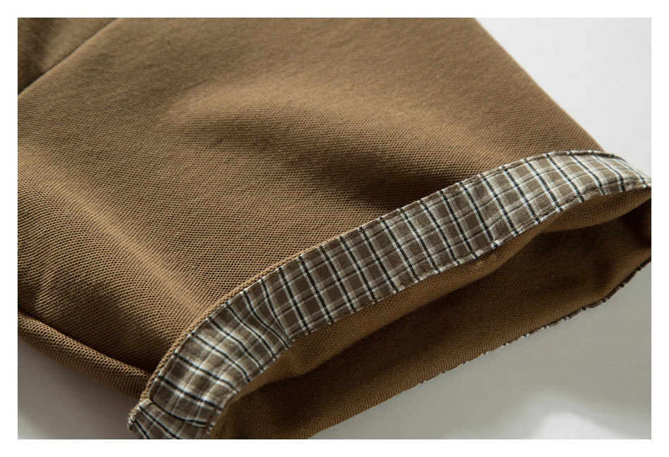 Close-up of a brown polo sleeve edge with brown, cream, and dark plaid trim.