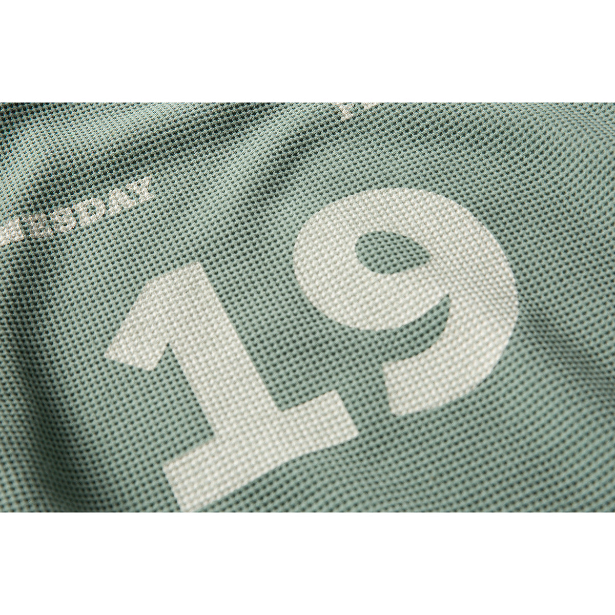 Close-up of a large ivory number 19 printed on sage-green textured sweatshirt fabric.