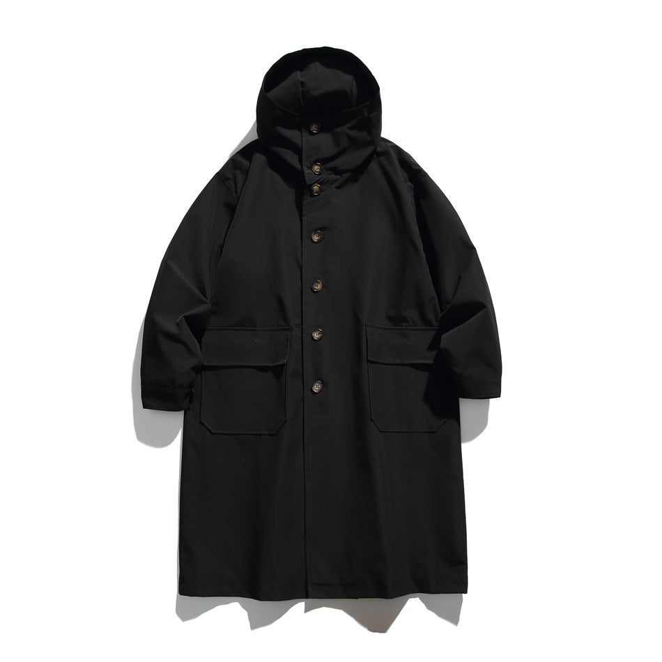 Black long hooded button-front coat with two large flap pockets, flat lay on a light background