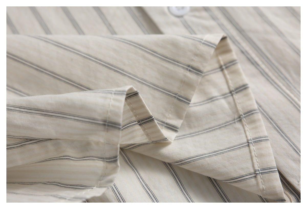 Close-up of a folded cuff on an ivory shirt with fine dark stripes.
