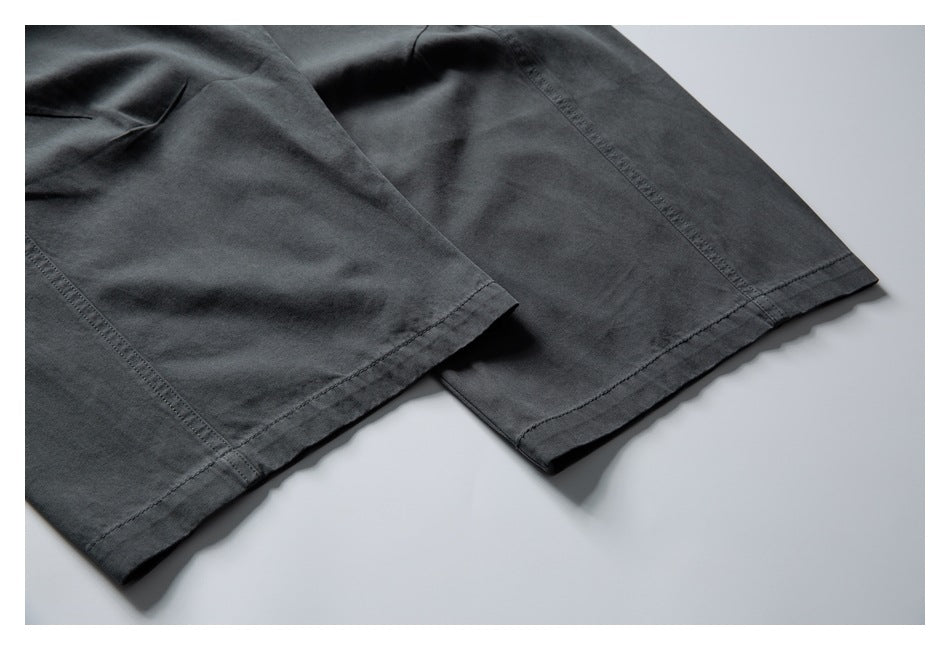 Close-up of dark charcoal pant legs showing straight stitched hems and panel seams.