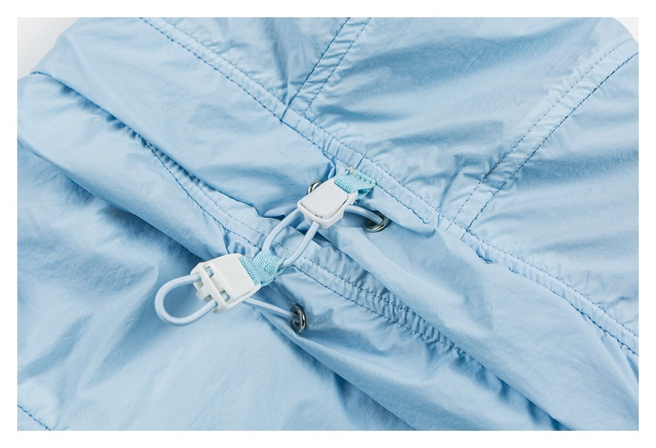 Close-up of a pale blue garment with stitched panels, metal eyelets, and a white drawcord toggle.
