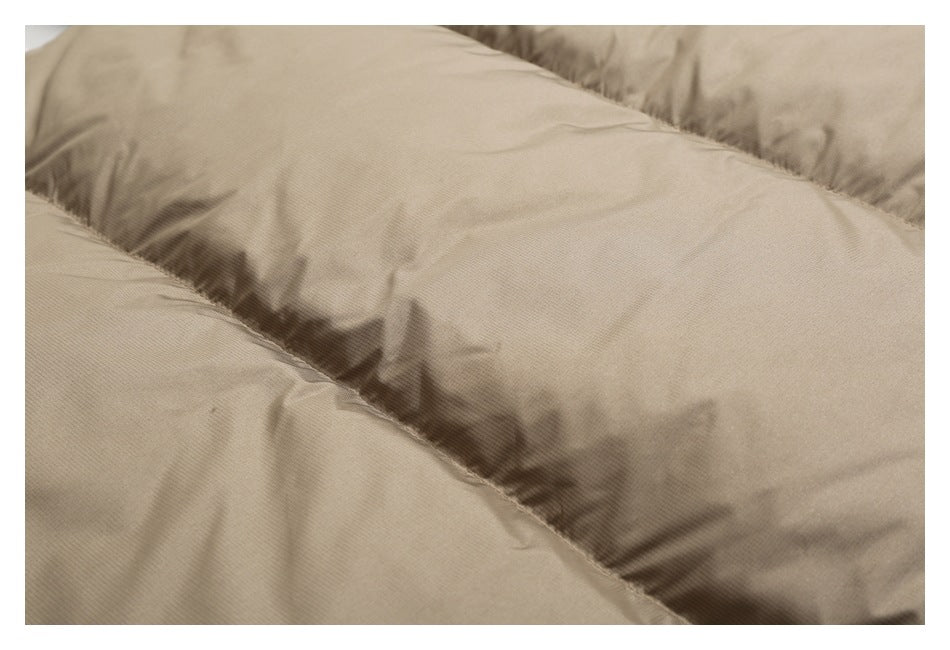 Close-up of taupe padded jacket fabric and curved stitched quilting seams.