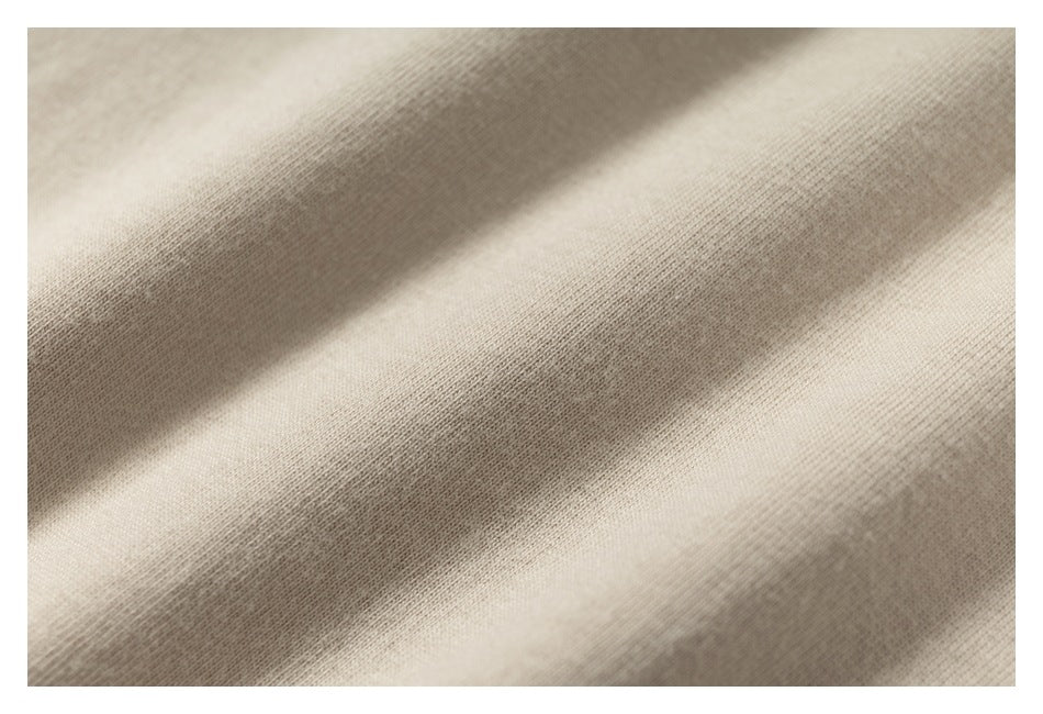 Close-up of light beige fabric showing a fine knit texture and soft folds.