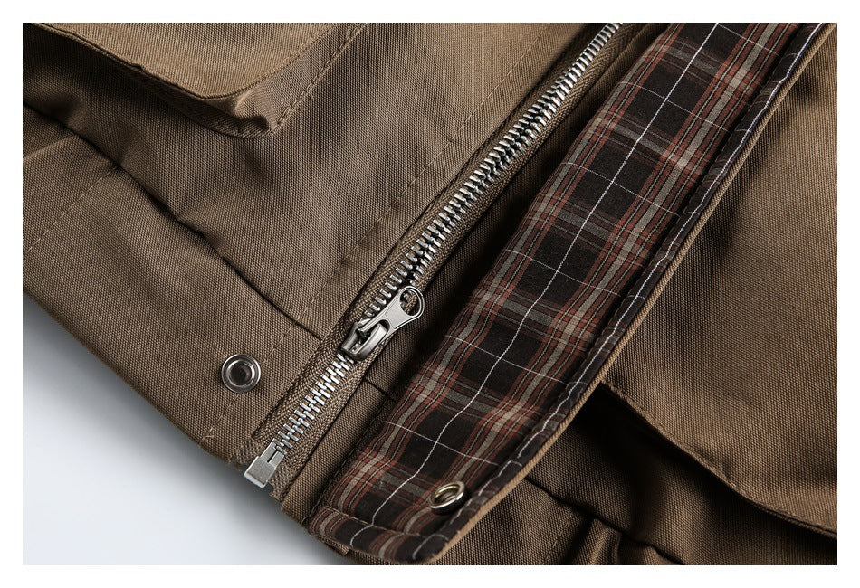Close-up of a brown garment's metal zipper, snap fastener, and brown plaid lining.