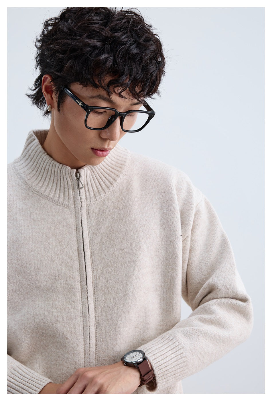 Close-up of a man wearing an ivory zip-front knit sweater with a ribbed stand collar and cuffs.